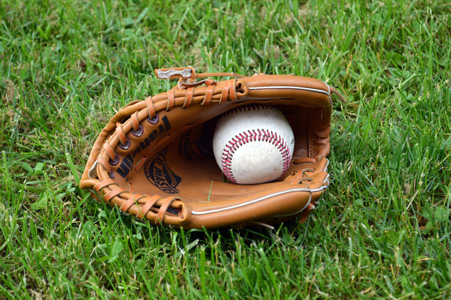 A white baseball on a brownish baseball catcher kept on a green lawn, encouraging to make the right choice with baseball equipment