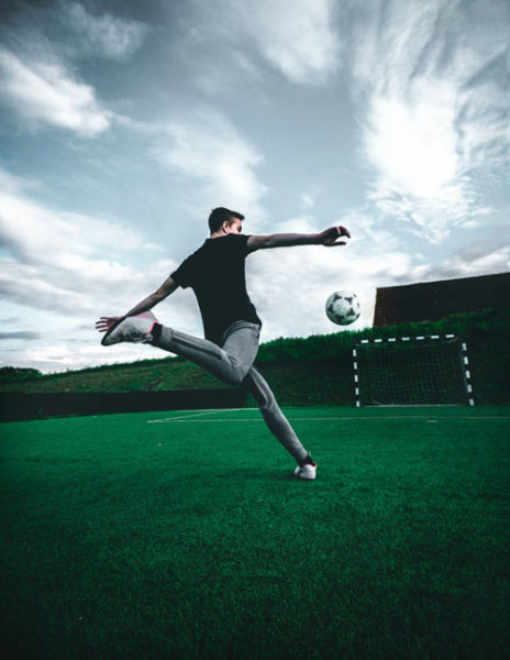 Image of a soccer player shooting soccer ball from the ground depicting the most important soccer protective gear