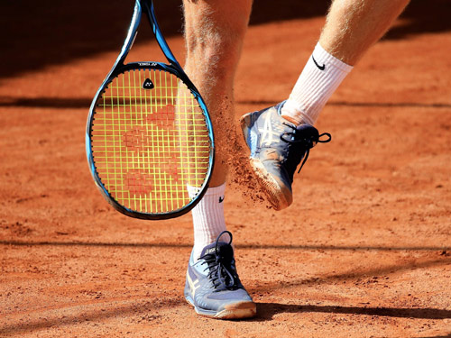 Image of a tennis racquet and a pair of tennis shoes by Asics, a world-renowned brand for tennis.