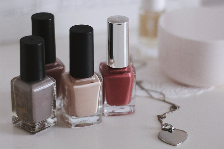 Image of brown gray, cream and light red nail polish bottles depicting best colors to paint your nails based on skin tone