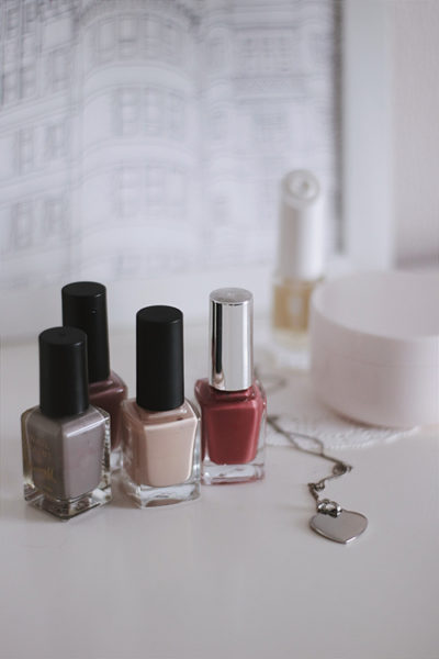 Image of brown gray, cream and light red nail polish bottles depicting best colors to paint your nails based on skin tone