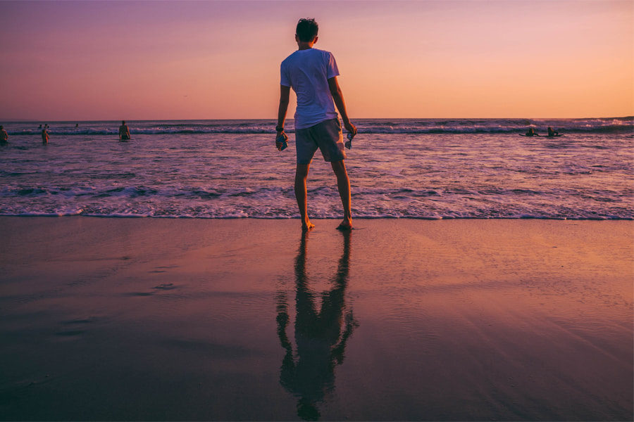 A man wearing a t-shirt and a pair of shorts at the beach denoting the best beach outfits for men