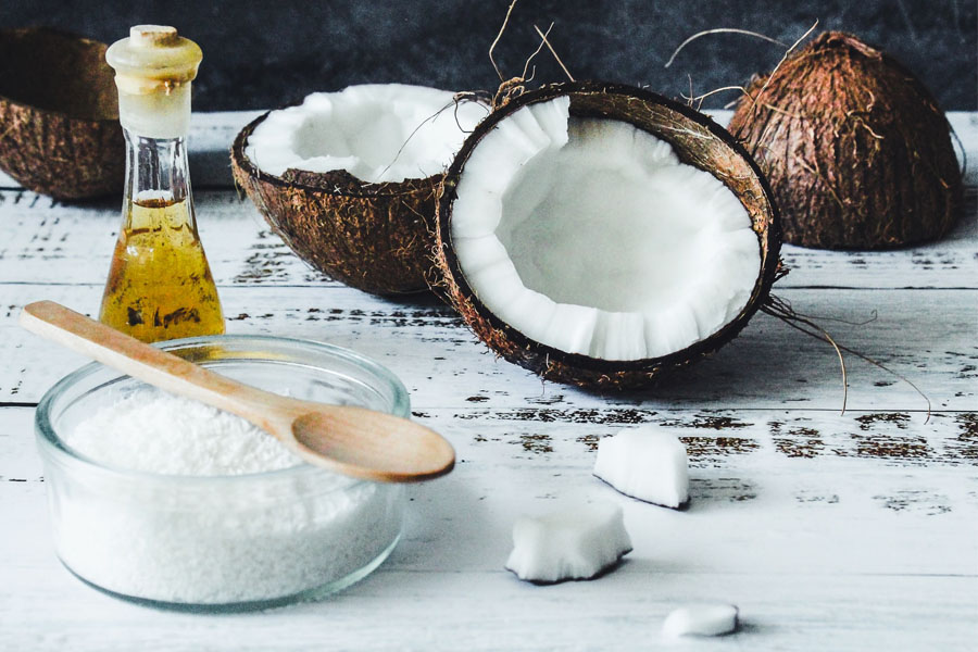Image of coconut oil and some broken coconuts depicting its amazing benefits