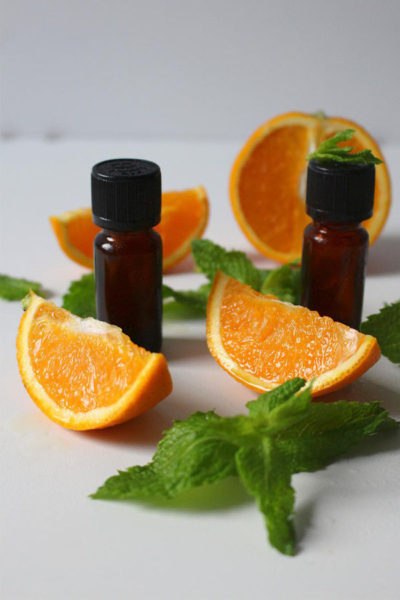 Image of orange slices and orange essential oil bottles depicting benefits of orange essential oil