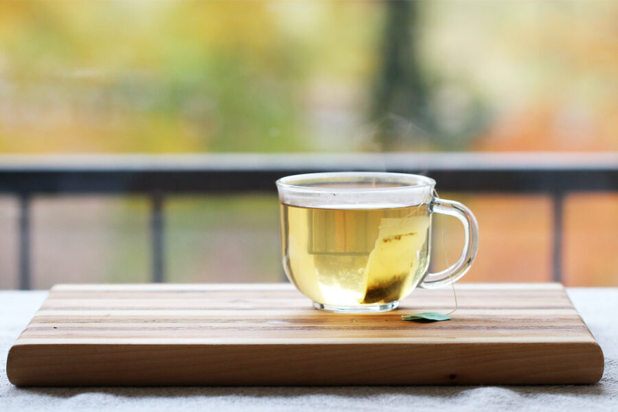 Image of a cup of green tea sitting on a wooden palette depicting the benefits of green tea