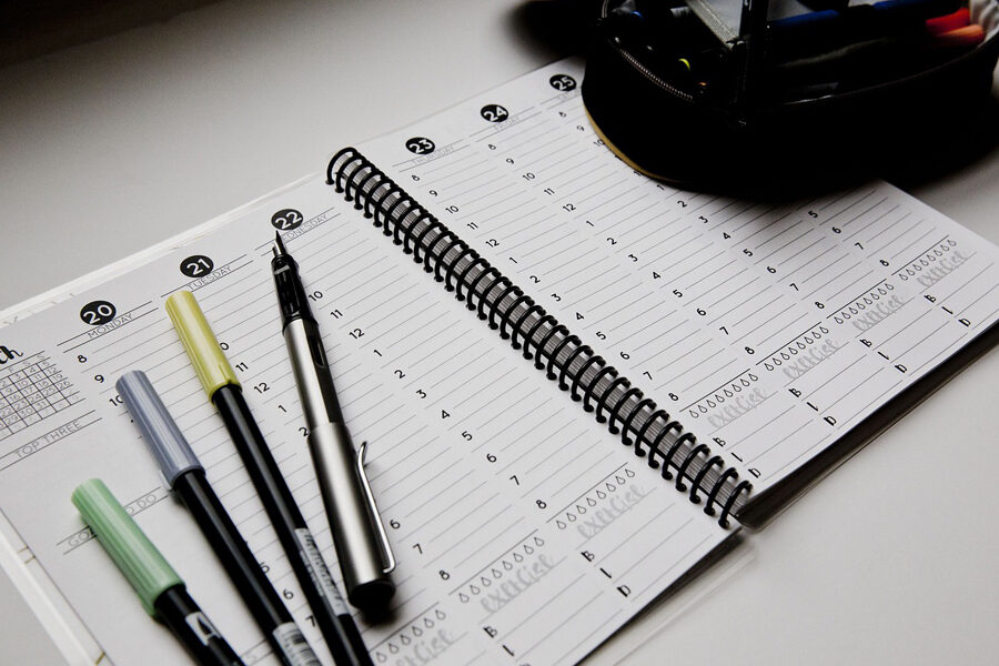 Image of a weekly planner along with some pens