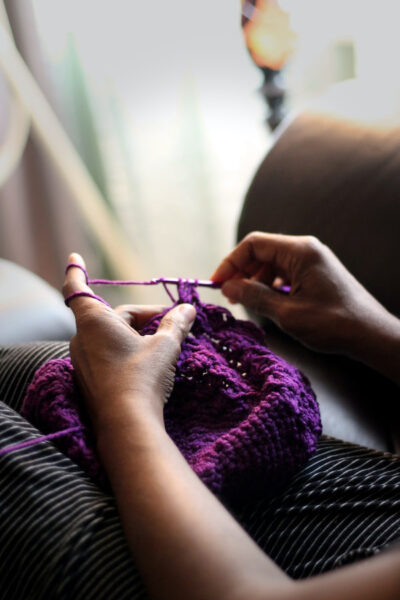 Image of a woman crocheting a beautiful purple textile depicting the wonder of this popular and rewarding hobby
